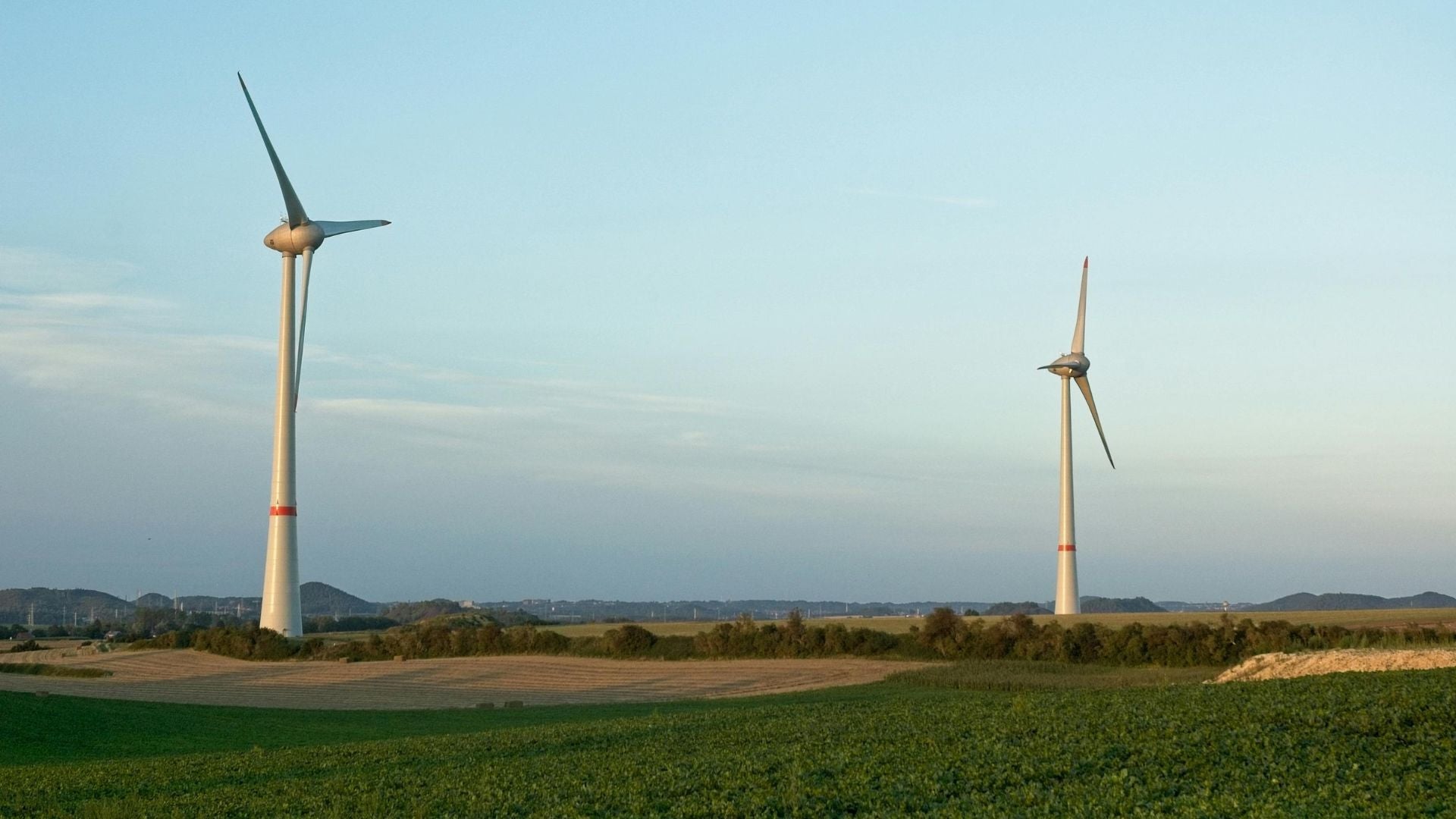 Wind turbines spinning on open farmland, symbolizing renewable energy and carbon-neutral power sources.