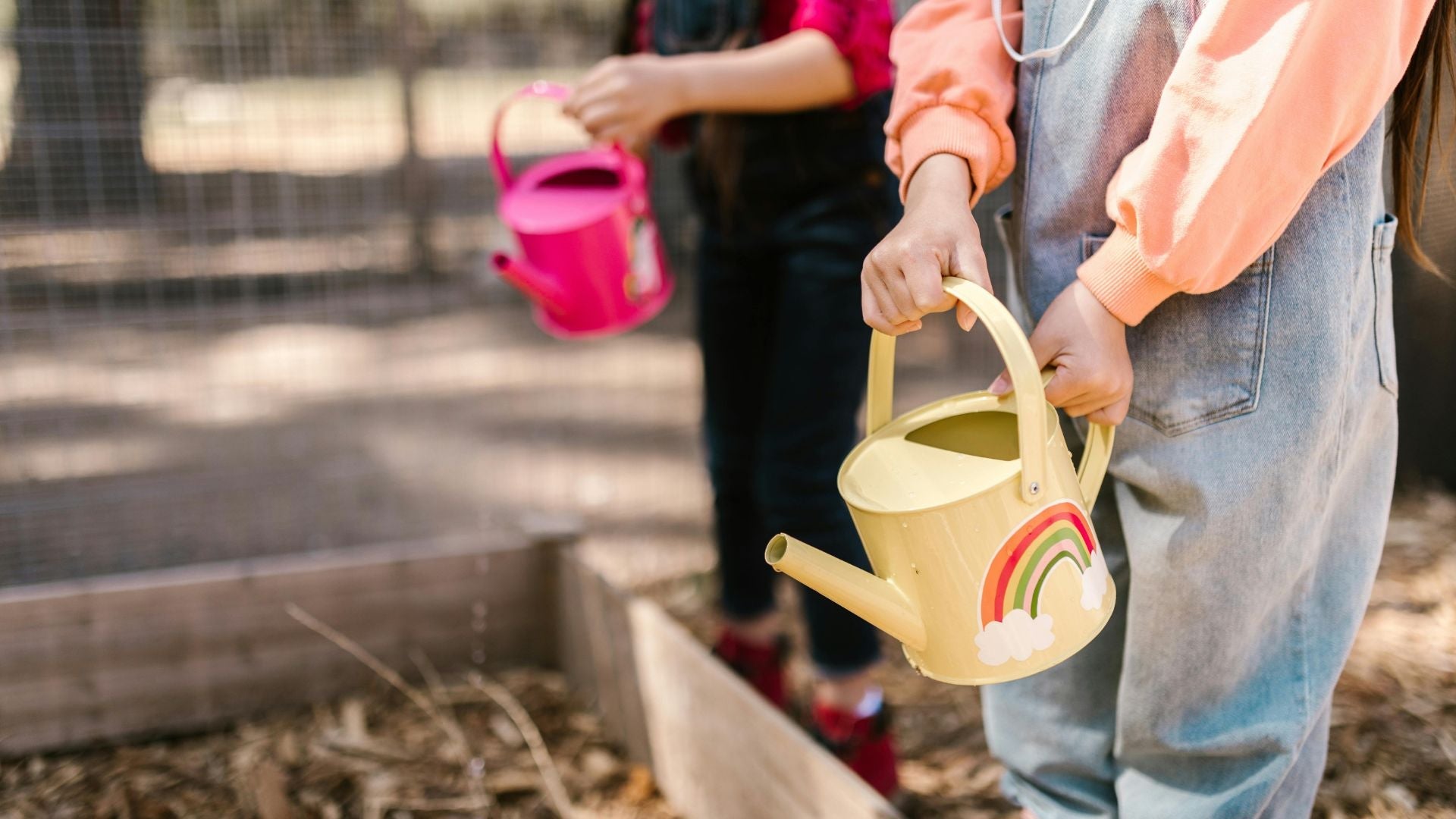 Children watering plants in a raised garden bed—encouraging eco-friendly habits from a young age as part of ecoHiny’s green parenting mission