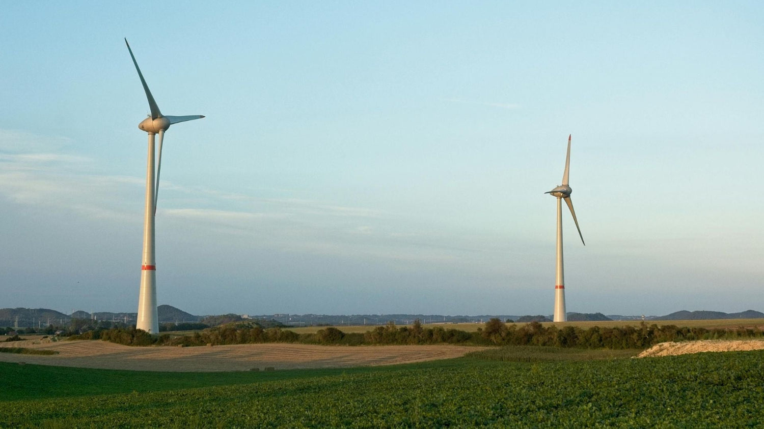 Wind turbines spinning on open farmland, symbolizing renewable energy and carbon-neutral power sources.
