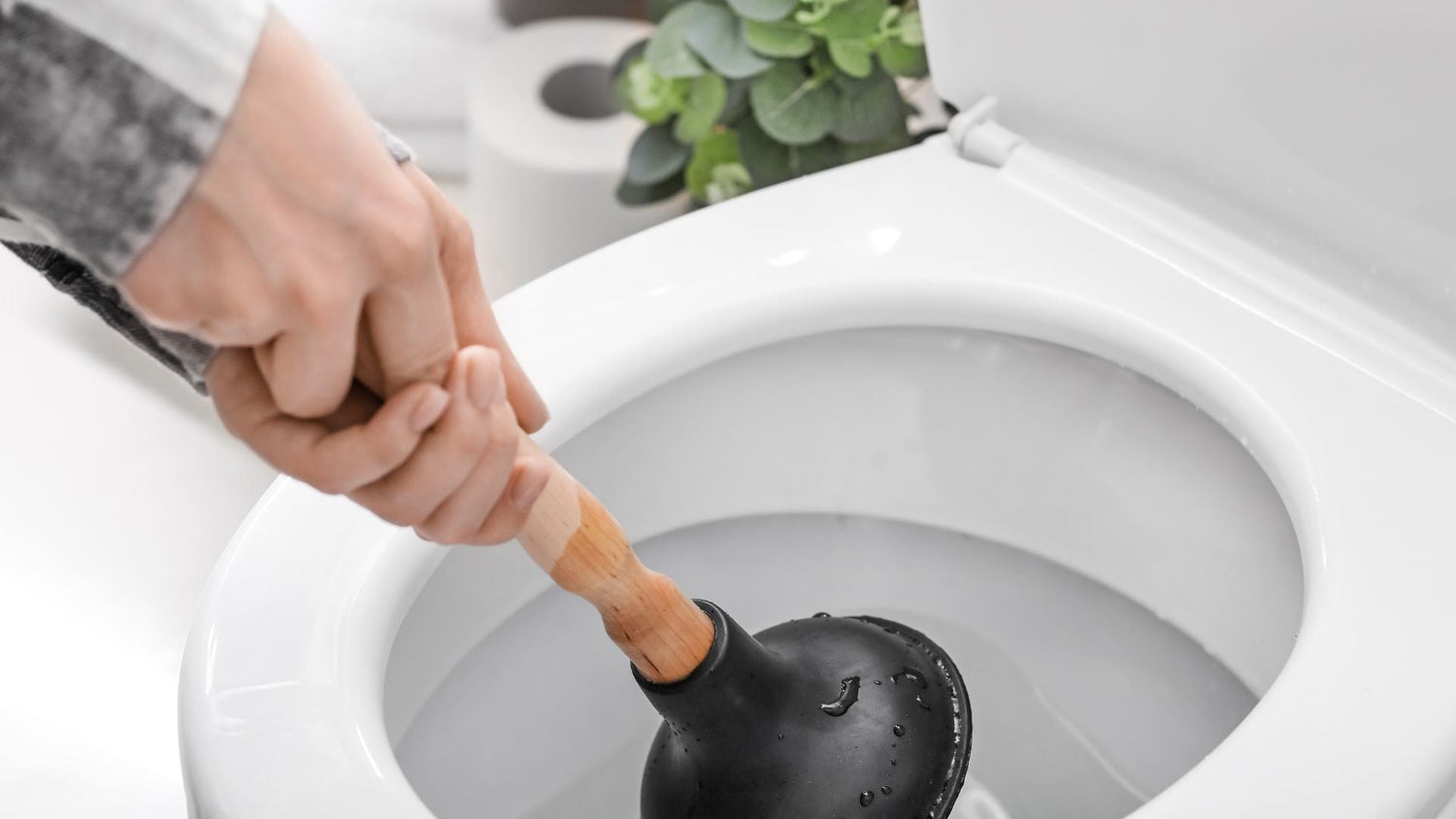 Person unclogging toilet with plunger, emphasizing the need for septic-safe, clog-free toilet paper like ecoHiny bamboo rolls