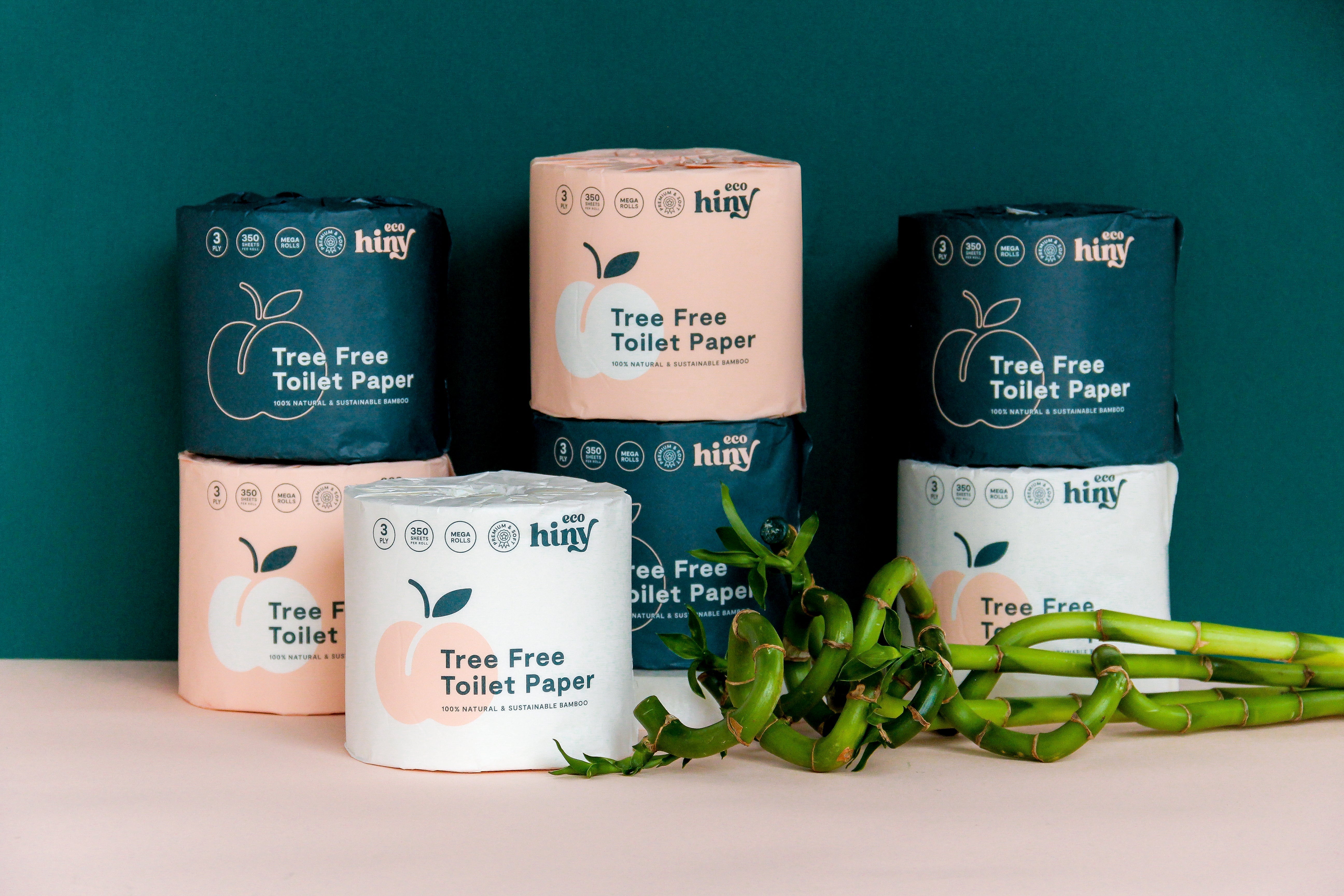 Stack of ecoHiny tree-free toilet paper rolls with sustainable bamboo packaging, emphasizing plastic-free, 3-ply bamboo toilet paper as an eco-conscious alternative