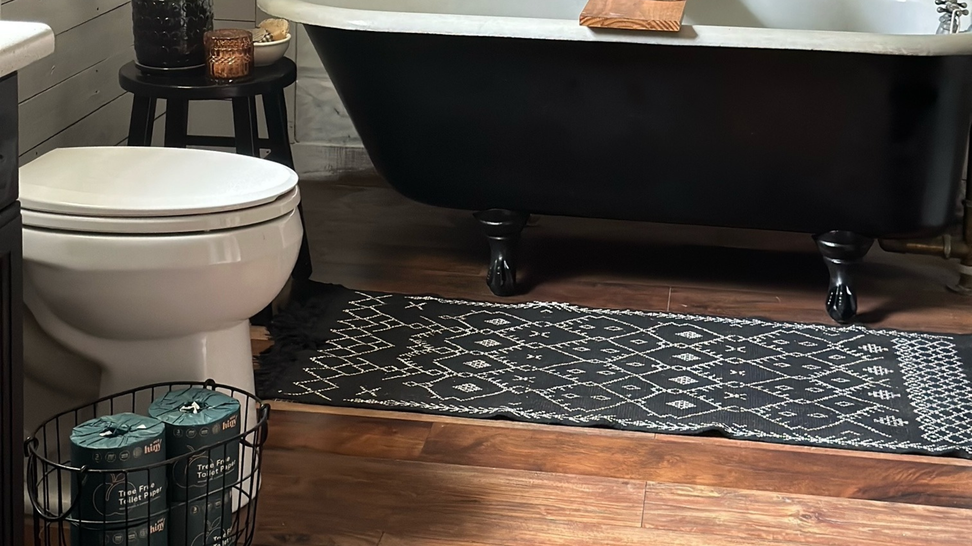 Stylish bathroom with ecoHiny toilet paper rolls neatly stored in a black wire basket next to the toilet.